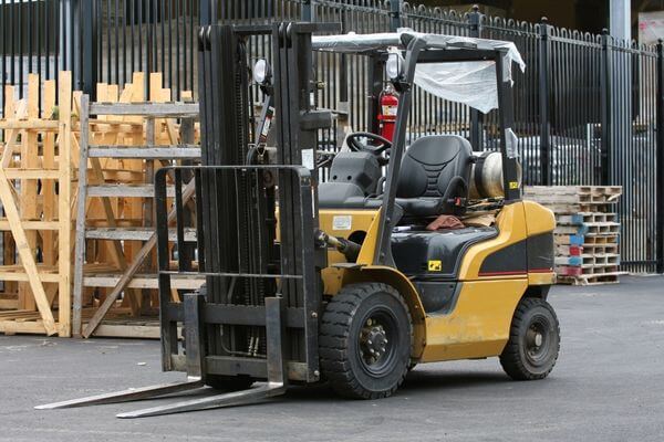 A forklift parked in front of a warehouse, showcasing its readiness for cold-weather logistics and challenging environments.