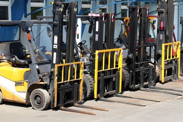 A row of forklifts parked in front of a building, ready for use in cold storage and industrial environments.
