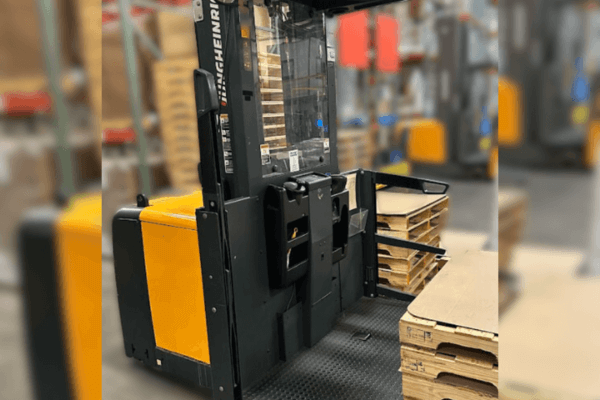 A forklift navigates a warehouse aisle, surrounded by boxes on the floor, illustrating efficient material handling in tight spaces.