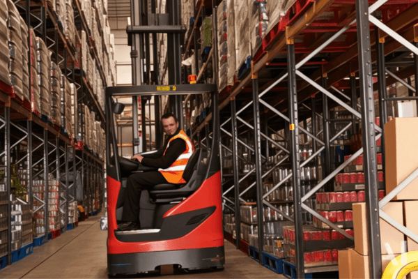 A man operating a forklift inside a warehouse, emphasizing the importance of quality in used forklifts for safety and efficiency.